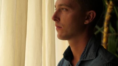 Pencereden bakan üzgün adam.