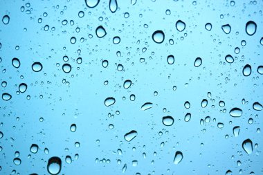 Yağmur mevsiminde araba camına çok su damlatılır. Mavi arka planda doğal yağmur..