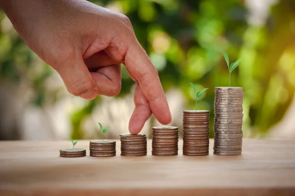 Male hand stacking coins with tree for the second step like growing for the future, education, home, loan and child on bokeh background.