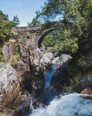 Montalegre 'nin simgesi, Ponte da Misarela. Eski köprü, bitki örtüsü, şelale ve su gökkuşağı manzarası.