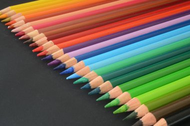 Koyu arkaplanda renkli kalemler, renkli kalemler, okula geri dönüş malzemesi, renkli kalemler, gökkuşağı tarzı.