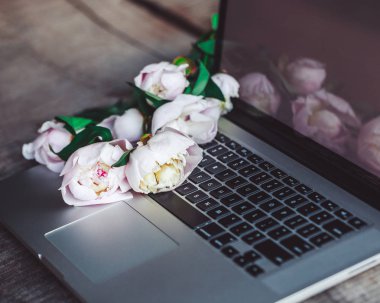 Dizüstü bilgisayar açık park peonies buket kaba ahşap tablo.