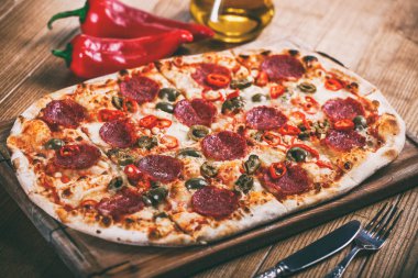 Salam, biber ve zeytin rustik tablo ile lezzetli biberli Pizza. Üstten görünüm. Tonlama