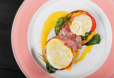 İngiliz kahvaltısı-kızarmış yumurta, ıspanak, domates, mozzarella peyniri ve koyu ahşap arka plan üzerinde plaka üzerinde jambon ile tost ekmeği. Sağlıklı gıda, üstten görünüm, düz yatıyordu