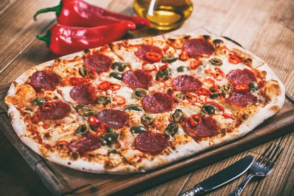 Salam, biber ve zeytin rustik tablo ile lezzetli biberli Pizza. Üstten görünüm. Tonlama