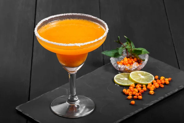 Alcoholic cocktail with sea buckthorn in a glass on dark background. Summer drinks and cocktails