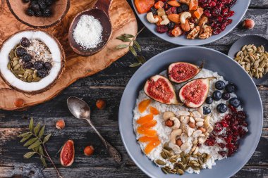 Pilav Hindistan cevizi yulaf lapası incir, çilek, fındık, Kuru kayısı ve plaka rustik ahşap zemin üzerine Hindistan cevizi sütü ile. Sağlıklı kahvaltı malzemeler. Yeme, vegan gıda kavramı temiz. Üstten görünüm