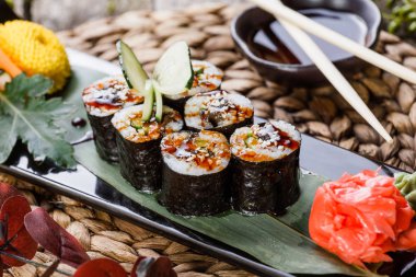 Suşi Roll - Maki Sushi füme yılan balığı, salatalık, avokado ve susam çiçeklerle süslenmiş bambu mat siyah taş. Japon mutfağı