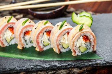 Suşi somon, krem peynir, kırmızı havyar, avokado ve wasabi kara taş üzerine bambu hasır, seçici odak üzerinde kümesiyle alır. Japon mutfağı