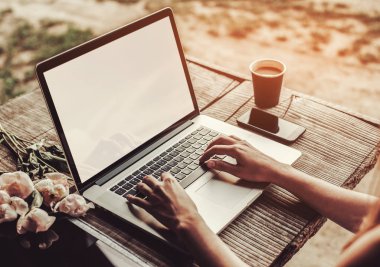 Kahve fincanı, çilek, şakayık çiçeği ve akıllı telefonlu kaba ahşap masada dizüstü bilgisayar kullanan ve daktilo kullanan genç bir kadın. Açık hava parkında çalışan serbest çalışan biri. Tonlama