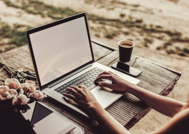 Kahve fincanı, çilek, şakayık çiçeği ve akıllı telefonlu kaba ahşap masada dizüstü bilgisayar kullanan ve daktilo kullanan genç bir kadın. Açık hava parkında çalışan serbest çalışan biri. Tonlama