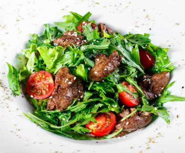 Sıcak kızarmış karaciğer, kiraz domates ve koyu ahşap zemin üzerine karışık yeşillik salatası. Sağlıklı gıda. Maddeler tablosundaki. Üstten görünüm