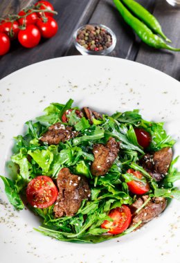 Sıcak kızarmış karaciğer, kiraz domates ve koyu ahşap zemin üzerine karışık yeşillik salatası. Sağlıklı gıda. Maddeler tablosundaki. Üstten görünüm