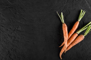 Karanlık bir taş zemin üzerine taze havuç grup. Gıda kavramı, üstten görünüm, kopya alanı