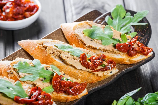 意大利三明治 Bruschetta 与肉头 芝麻菜 晒干西红柿和种子在 Ciabatta 面包上的黑木桌上 美味的小吃 三明治 开胃小菜 — 图库照片