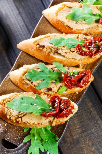 意大利三明治 Bruschetta 与肉头 芝麻菜 晒干西红柿和种子在 Ciabatta 面包上的黑木桌上 美味的小吃 三明治 开胃小菜 — 图库照片