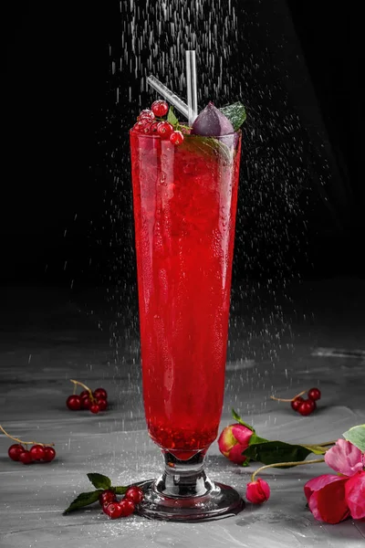 Cold red cocktail with red currant, orange and ice in tall glass on dark background. Summer drinks and alcoholic cocktails