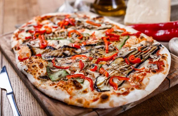 Delicious pizza with chicken, zucchini, eggplant, pepper, cheese and mushrooms on wooden rustic table. Top view. Toning