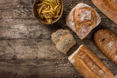 Farklı taze ekmek ve un ürünleri makarna rustik ahşap zemin üzerinde. Yaratıcı düzen ekmek yaptım. Sağlıklı gıda kavramı, üstten görünüm, düz yatıyordu, kopyalama alanı