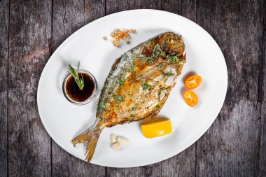 Yeşiller ve ahşap zemin üzerine limon ile ızgara dorado balık. Üstten görünüm. Sağlıklı gıda. Üstten görünüm.