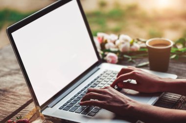 Kullanarak ve dizüstü bilgisayar, sert ahşap masa kahve fincanı, çilek, buket peonies çiçek ile yazarak genç kadın.