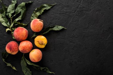 Olgun şeftali siyah taş zemin üzerine. Sağlıklı gıda kavramı, üstten görünüm, kopya alanı.