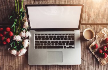 Dizüstü bilgisayar, buket peonies çiçekler, kahve, sert ahşap masa üzerinde çilek ile çalışma alanı