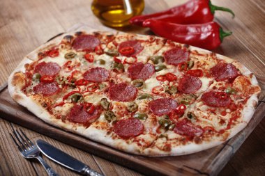 Salam, biber ve zeytin rustik tablo ile lezzetli biberli Pizza. Üstten görünüm. Tonlama.