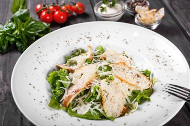 Tavuk göğsü, parmesan peyniri, kruton, karışık yeşillik, ahşap arka plan üzerinde marul salatası. Sağlıklı gıda. Maddeler tablosundaki