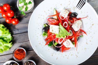 Yunan salatası ile domates, salatalık, kırmızı soğan, zeytin, beyaz peynir ve tatlı biber ahşap arka plan üzerinde organik sebze. Sağlıklı gıda. Üstten görünüm