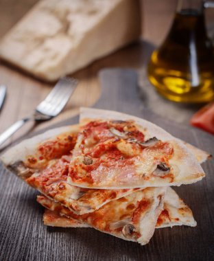 Dilimlenmiş jambon pizza, ahşap kesme tahtası üzerinde peynir, mantar ve domates sosu. Üstten görünüm.