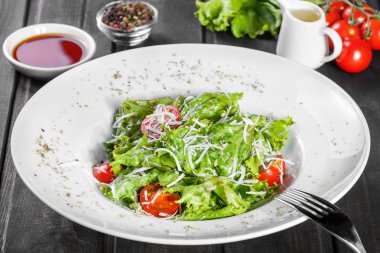 Karışık yeşillik, domates, ahşap zemin üzerine parmesan peyniri ile taze salata. Sağlıklı gıda. Maddeler tablosundaki.