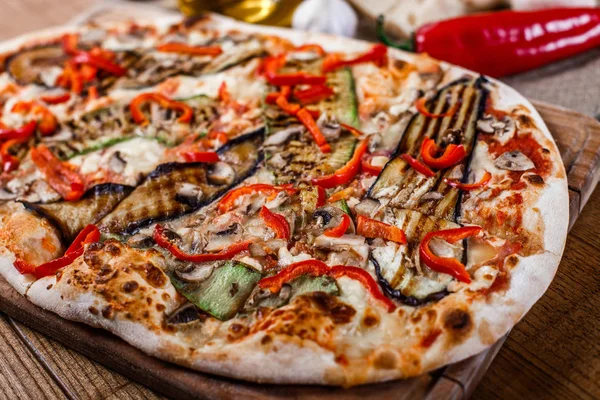 Delicious pizza with chicken, zucchini, eggplant, pepper, cheese and mushrooms on wooden rustic table. Top view. Toning.
