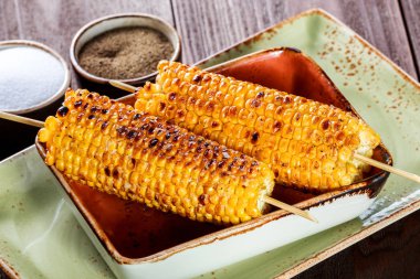 Izgarada mısır tuz ve koyu ahşap arka plan, Closeup tabakta üzerine tereyağı ile. Maddeler tablosundaki.