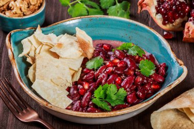 Meze ile kırmızı fasulye, ceviz, tereyağı, kişniş, maydanoz, fişleri ahşap arka plan üzerinde plaka üzerinde. Sağlıklı gıda. Üstten görünüm.