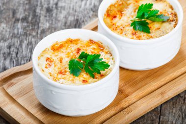 Sulu tavuk, mantar, krema sos ve peynir kesme tahtası ahşap arka plan üzerinde üzerinde sıcak Julienne iki kâse. Etli meze