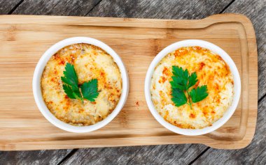 Sulu tavuk, mantar, krema sos ve peynir kesme tahtası ahşap arka plan üzerinde üzerinde sıcak Julienne iki kâse. Etli meze