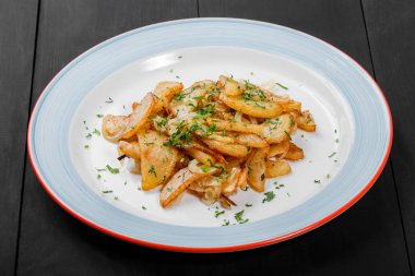 Çatal, ev yapımı yemekler ile koyu ahşap arka plan üzerinde plaka üzerinde otlar ile kavrulmuş patates. Üstten görünüm.