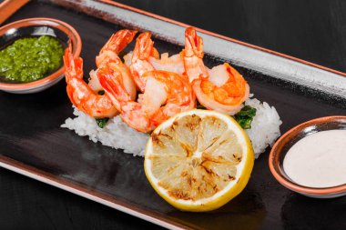 Karides karides sos, yeşillik ve ahşap arka plan üzerinde siyah plaka üzerinde pirinç ile kavrulmuş. Lezzetli yemek deniz ürünleri. Japon mutfağı. Üstten görünüm