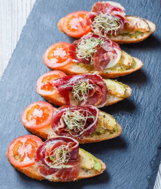 Meze bruschetta salam, domates, kabak ciabatta ekmeği taş arduvaz arka plan üzerinde tarih ile kapatın. Lezzetli aperatifler, sandviçler, crostini, parti ya da piknik zamanında antipasti. Üstten Görünüm