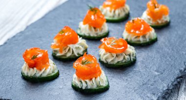 Meze kanepe somon, salatalık ve kayrak taş zemin üzerine krem peynir ile kapatın. Lezzetli aperatifler, sandviçler, crostini, brushetta, parti ya da piknik zamanında antipasti. Üstten Görünüm