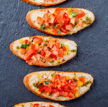 Meze bruschetta ciabatta ekmeği kayrak taş zemin üzerine doğranmış sebze ile kapatın. Lezzetli aperatifler, sandviçler, crostini, kanepe, parti ya da piknik zamanında antipasti. Üstten Görünüm