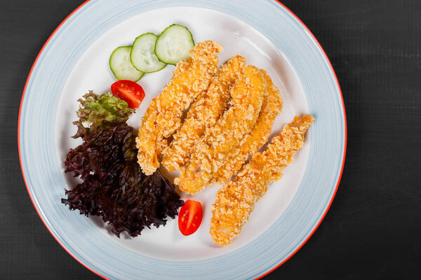 Fried salmon fillet with vegetables salad on black plate on dark background. Delicious dish of seafood.