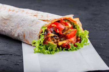 Izgara sebze ve marul üzerine koyu ahşap arka plan vejetaryen Burrito sarar. Sağlıklı yemek.