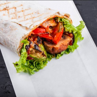 Izgara sebze ve marul üzerine koyu ahşap arka plan vejetaryen Burrito sarar. Sağlıklı yemek.