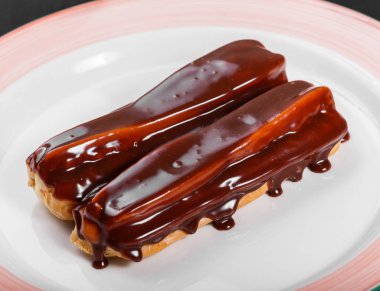 Koyu ahşap arka plan, tatlı gıda üzerine plaka üzerinde çikolata eklerleri.