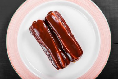 Koyu ahşap arka plan, tatlı gıda üzerine plaka üzerinde çikolata eklerleri.