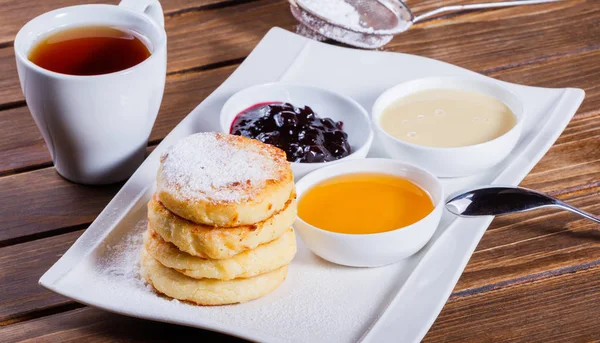 Kızartma ev yapımı peynir krep syrniki pudra şekeri, ekşi krema, Çilek reçel plaka üzerine kapatın. Hafta ya da Shrovetide krep geleneksel Rus mutfağı. Düz yatıyordu. Üstten görünüm