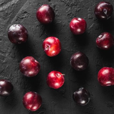 Karanlık taş zemin üzerine taze erik desen. Sağlıklı yaz meyve. Üstten görünüm, düz yatıyordu.