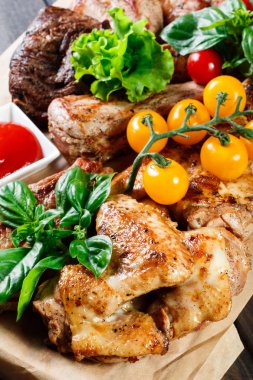 Çeşitli lezzetli ızgara et ve sebze taze salata ve kesme tahtası üzerinde ahşap arka plan Barbekü sosu ile kapatın. Sıcak et yemekleri büyük kümesi. Üstten görünüm